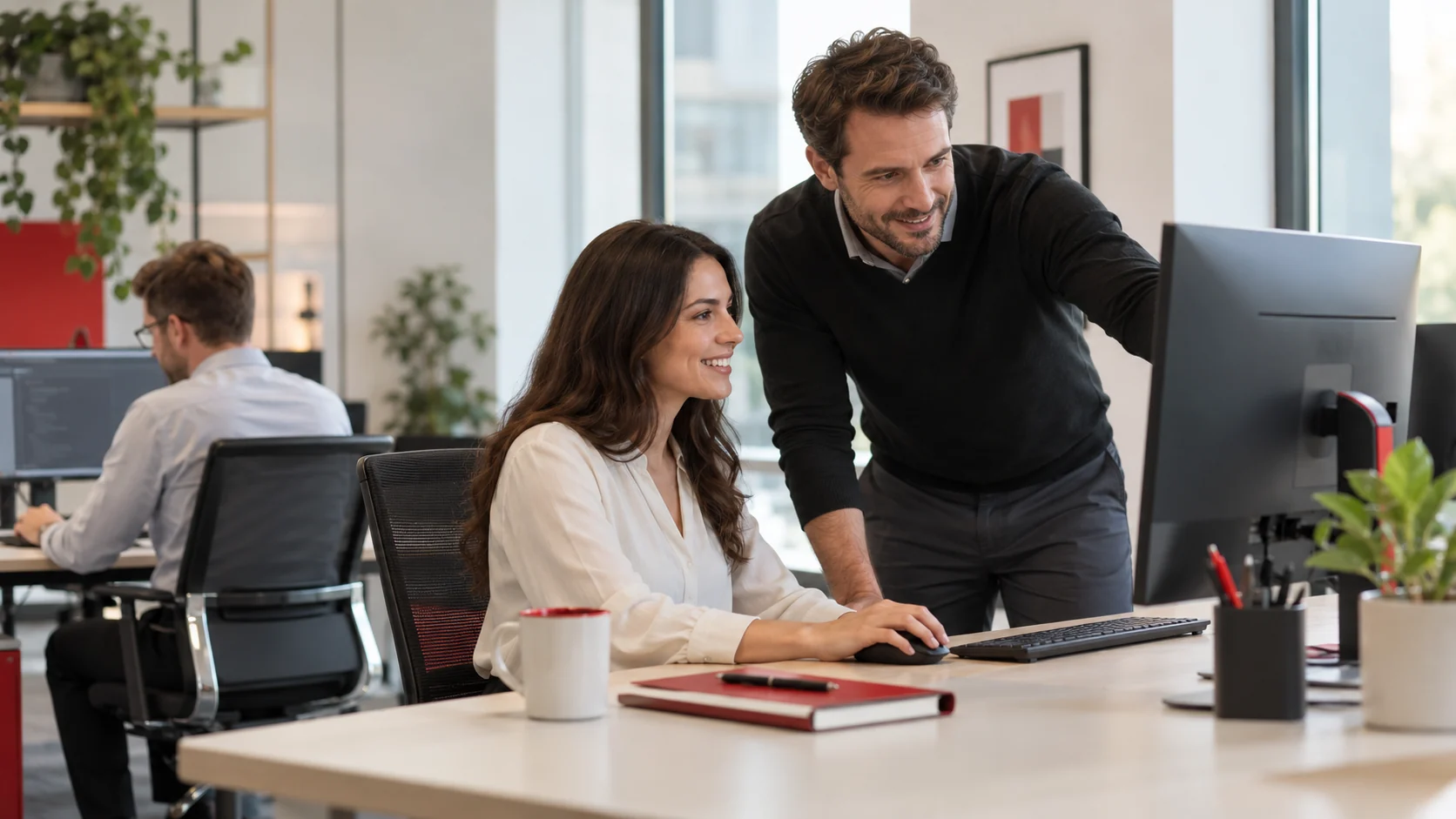 Office employee and a colleague working together at a desktop computer